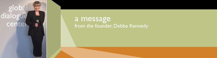 a banner with the words, a message from the founder, Debbe Kennedy with her photo standing in the lobby of the Global Dialogue Center